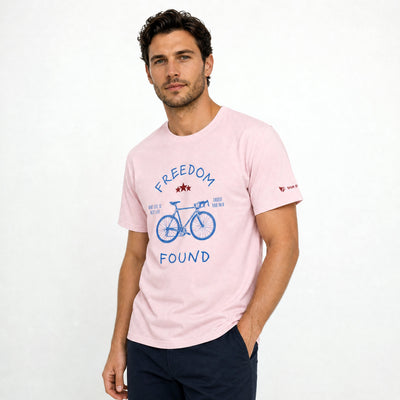 Man wearing a pink t-shirt with a bicycle graphic and text on a light gray background