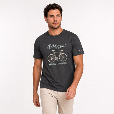 A man wearing a dark charcoal gray graphic t-shirt with a white bicycle design and the text 'Bike is Trust' and 'KEEP CALM & PEDAL ON'.
