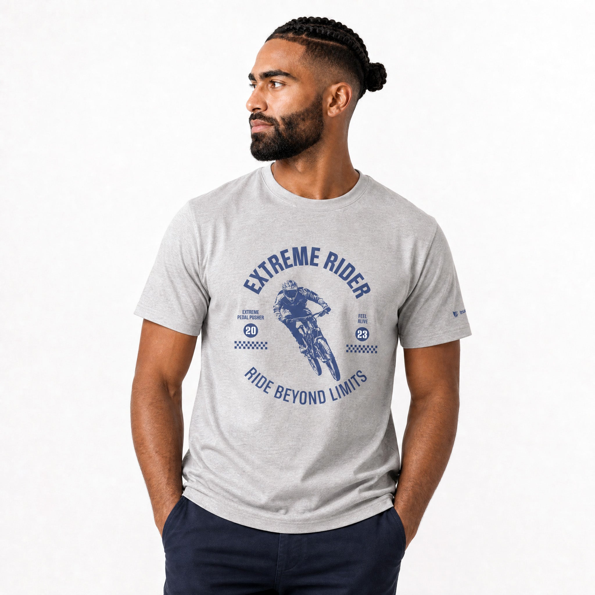 A man wearing a light gray heather t-shirt with a blue graphic print that reads 'EXTREME RIDER' and 'RIDE BEYOND LIMITS', paired with dark navy pants, set against a plain white studio background.