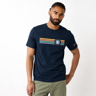 Man wearing a navy blue t-shirt with colorful stripes and a logo on a white background