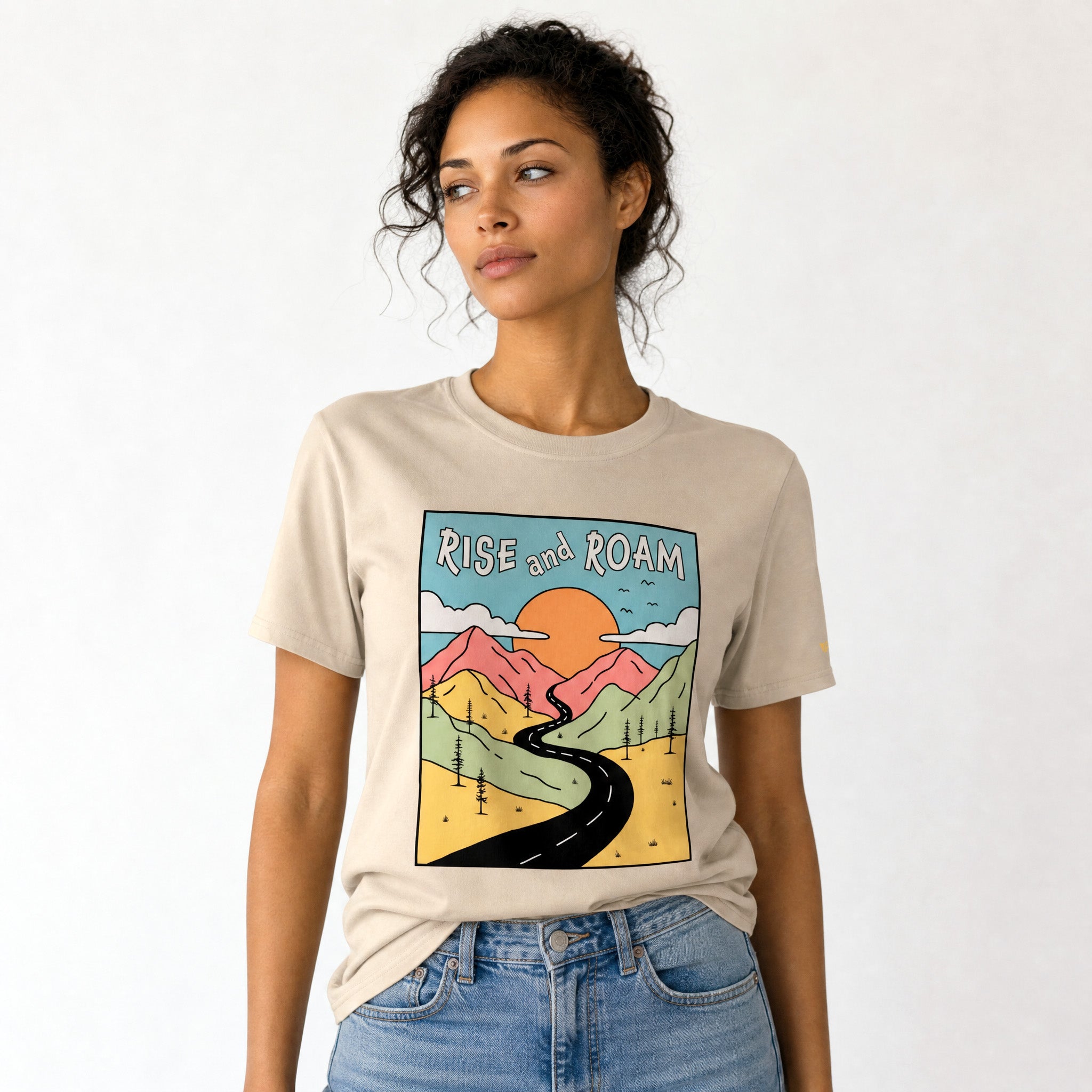 Woman wearing a beige t-shirt with a graphic design and text 'Rise and Roam' on a white background