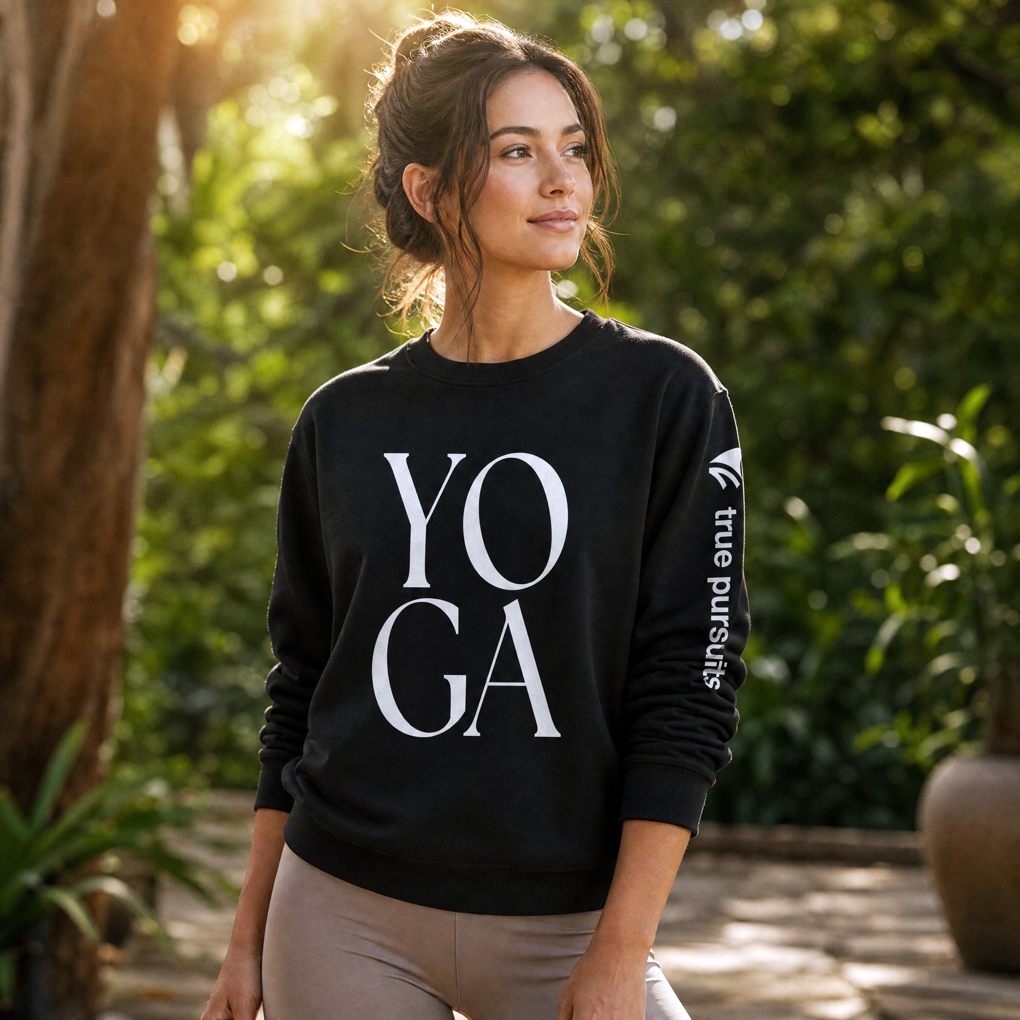 Woman wearing a black 'Yoga' sweatshirt in a garden setting